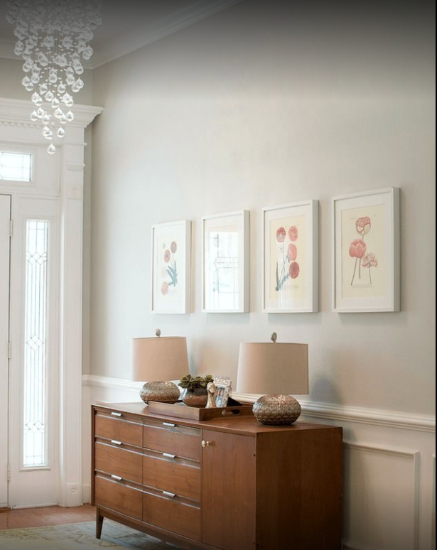 floor standing cabinet with 2 lamps and photos of flamingos hanging above it.